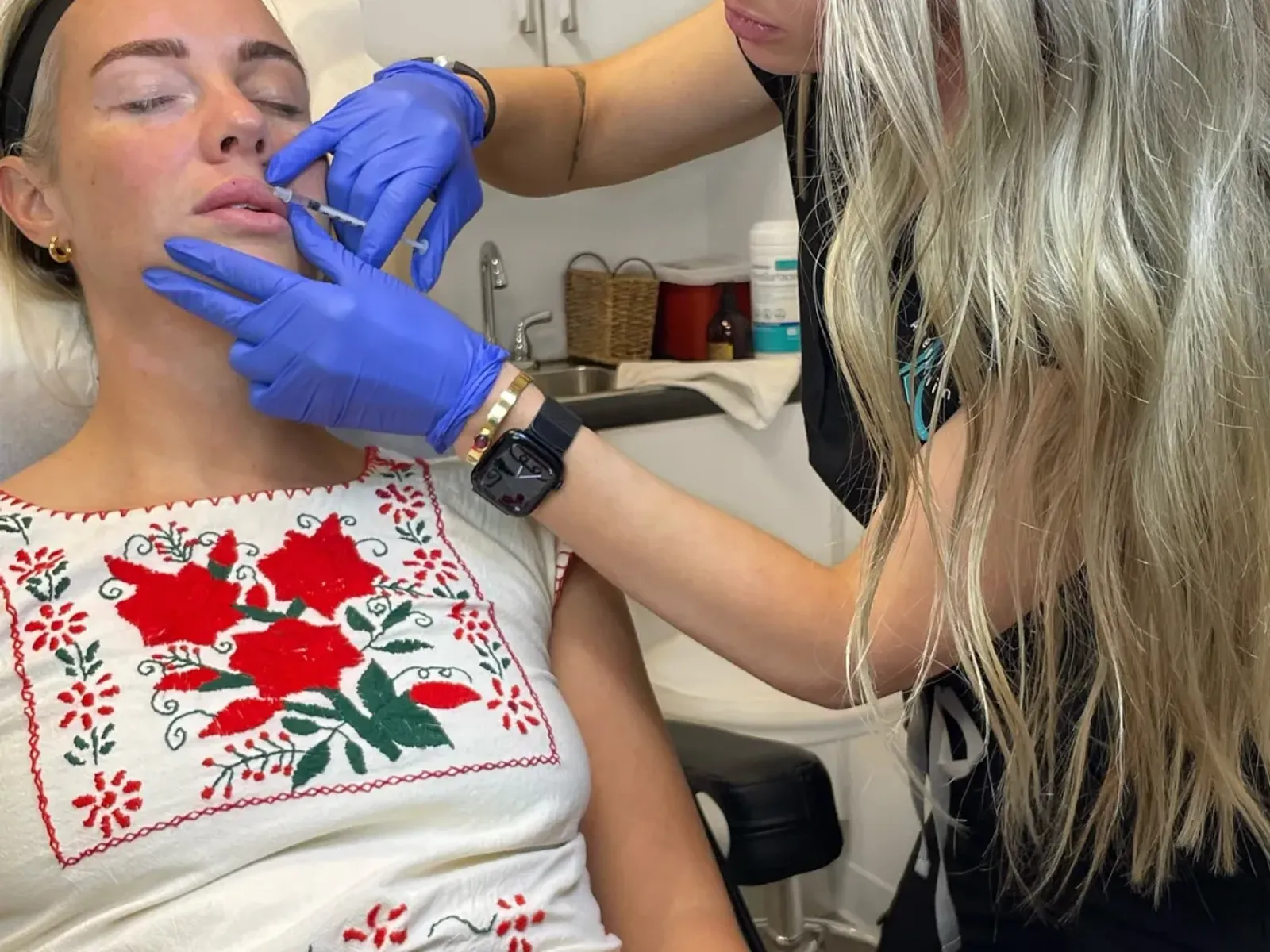 An Ageless Living nurse injector in gloves performing a dermal filler treatment along a patient's cheek