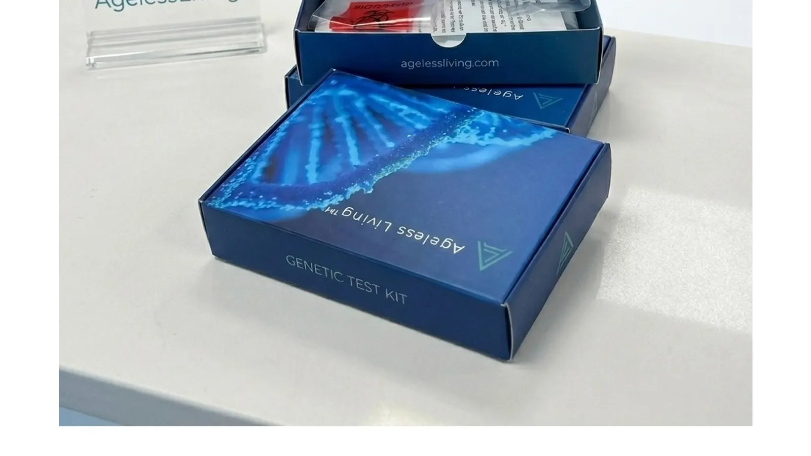 An open Ageless Genetics DNA test kit box with its blue packaging on a clinic counter