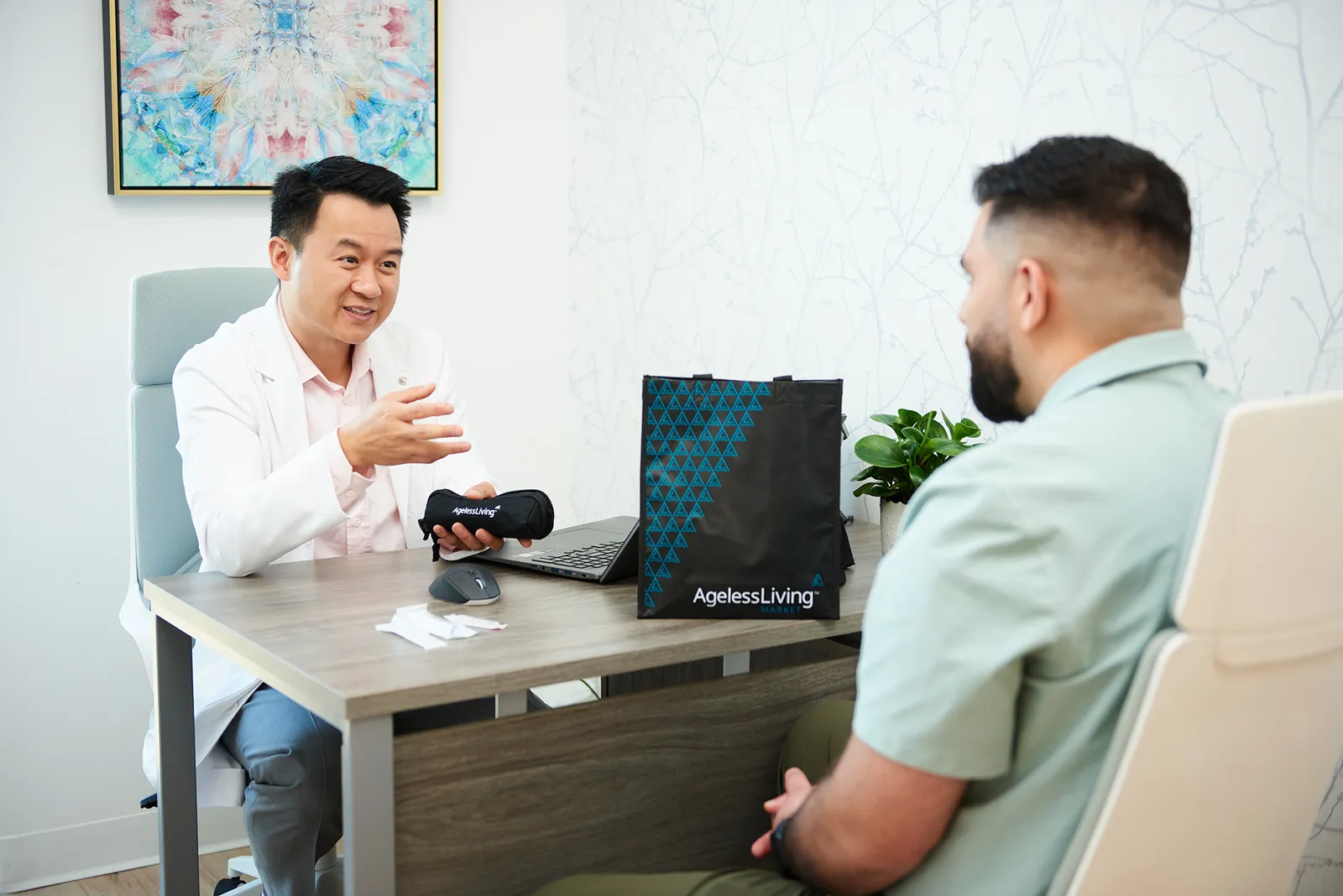An Ageless Living physician in consultation with a male patient across the desk at the Langley clinic