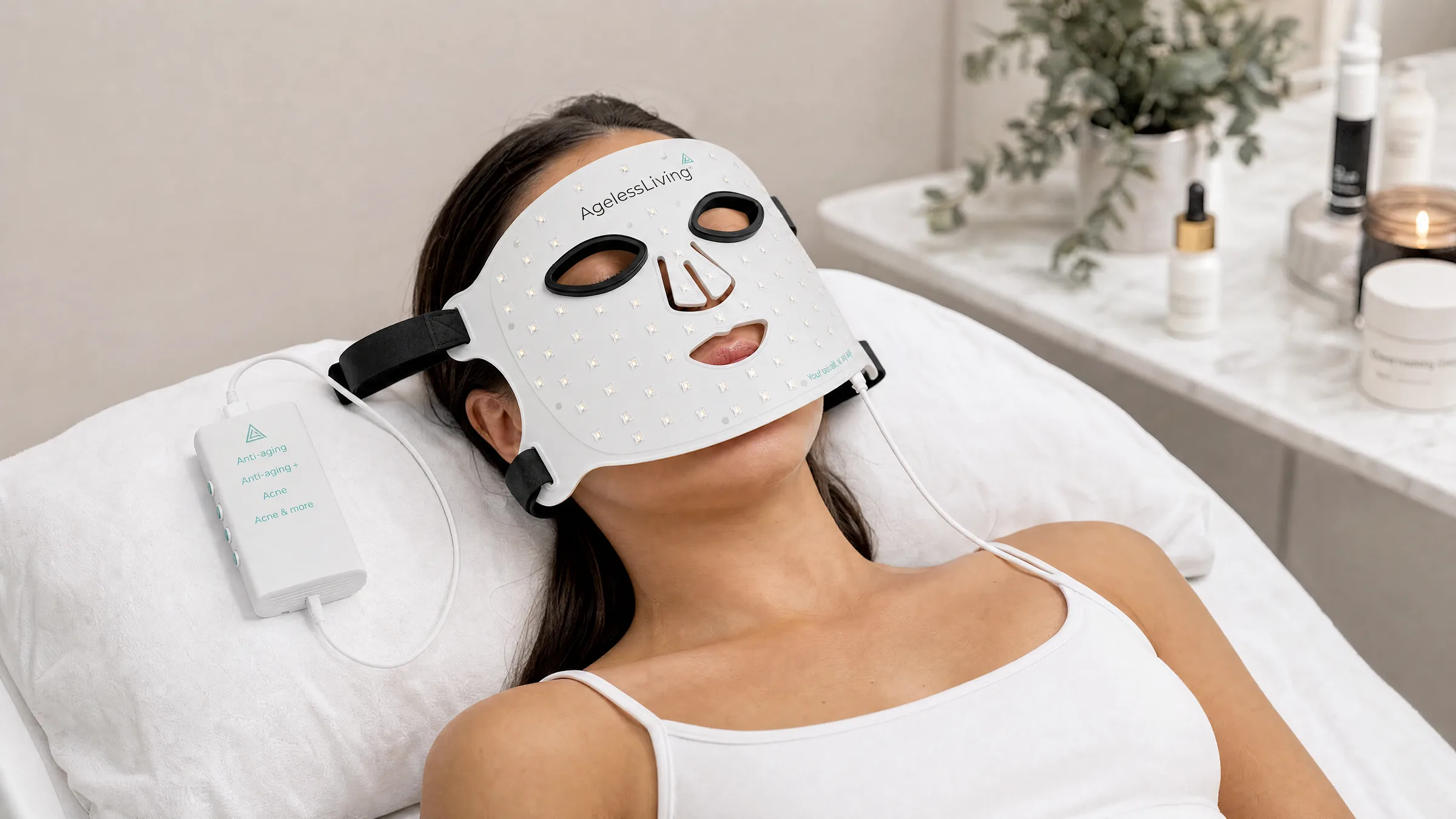 Someone lying back on a treatment bed wearing an Ageless Living LED face mask